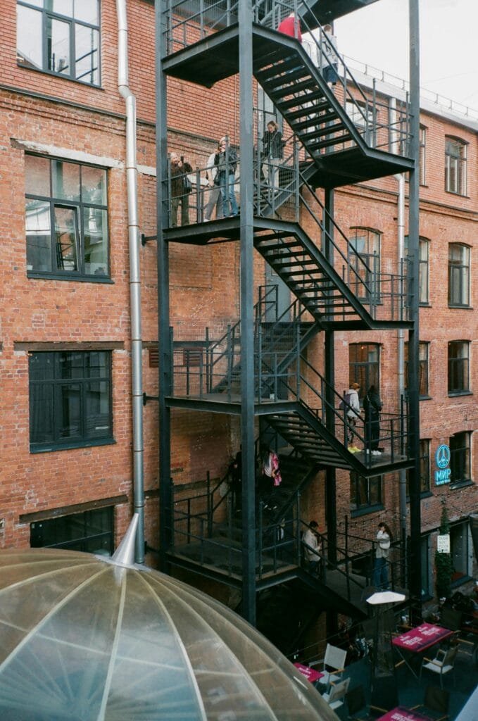 Brick building exterior with fire escape, people, and urban vibe.